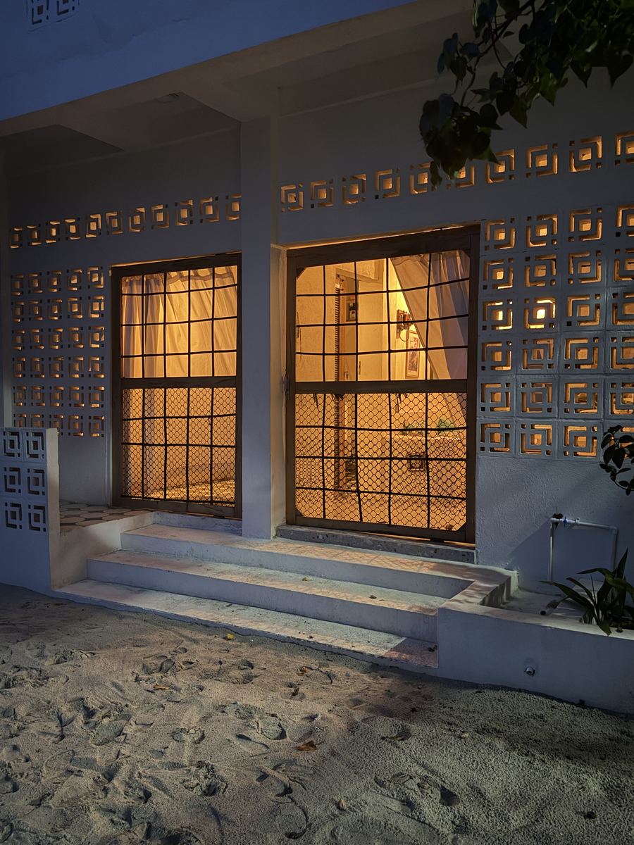 Entrada de la casa al anochecer, con las puertas iluminadas