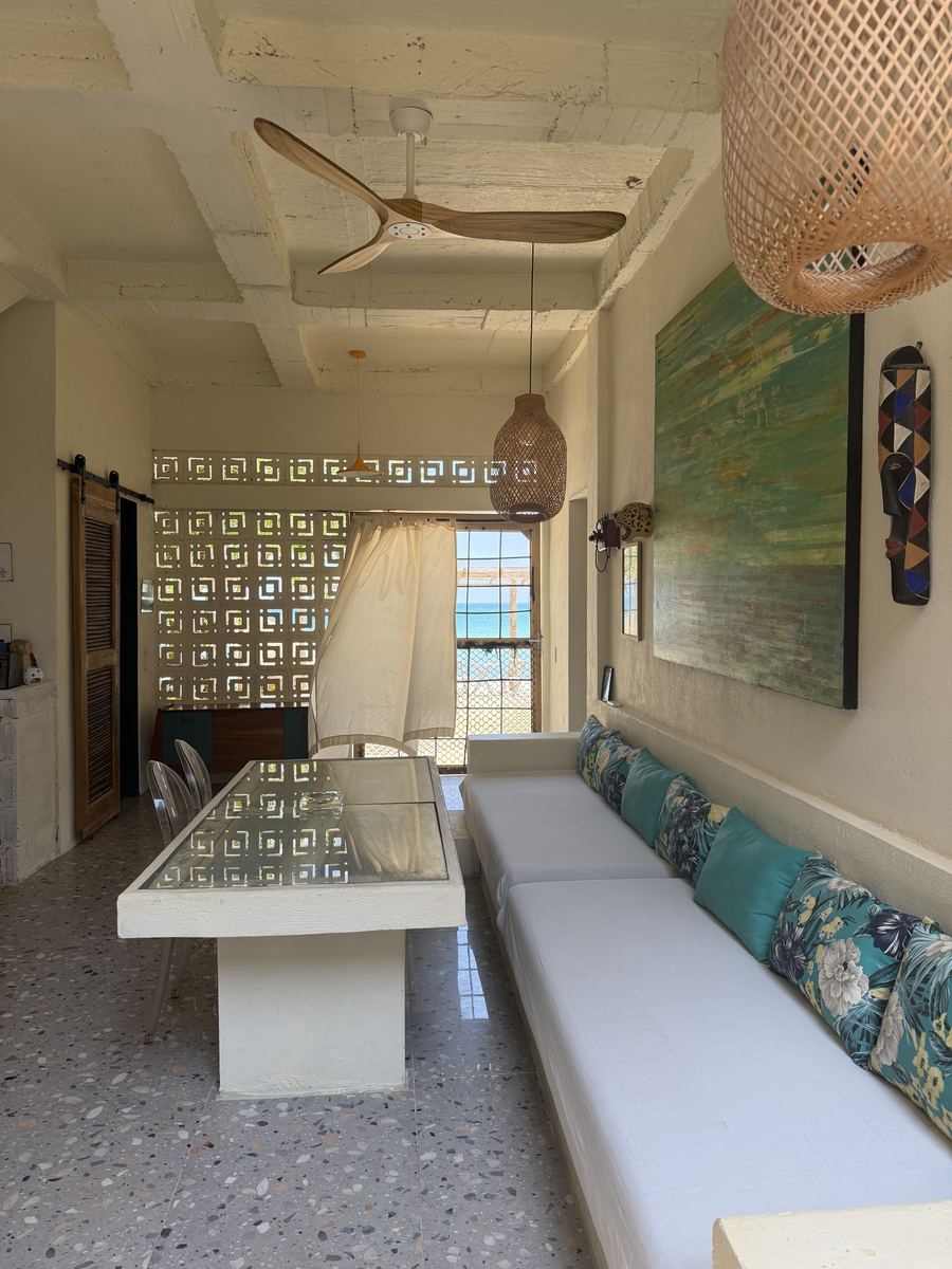 Mesa larga y sofá corrido junto a la ventana al mar