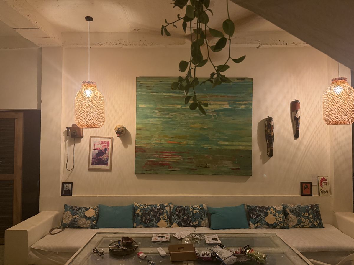 Sala con pintura verde, lámparas de mimbre y cojines de mar