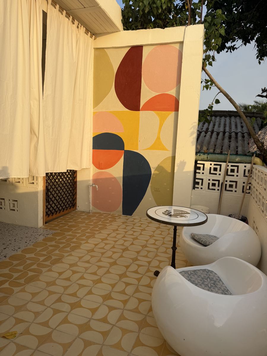 Terraza con mural geométrico de colores y sillas blancas