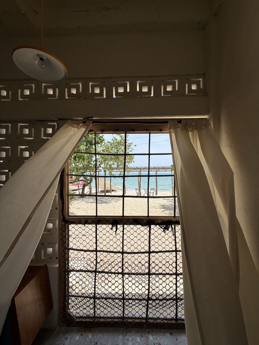 Ventana con cortinas blancas abierta a la playa